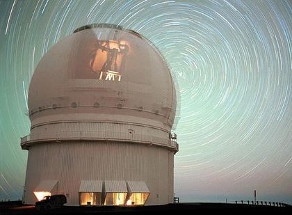 Photo extérieure d'un bâtiment blanc à dôme. Une image est projetée sur le dôme et l'arrière-plan est fait de cercles concentriques lumineux de diverses couleurs.