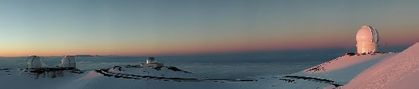 Panoramic photo of four observatories in a snowy landscape bathed in pinkish light at dusk