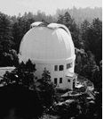 Black and white aerial photo of a white building with a domed roof, surrounded by trees