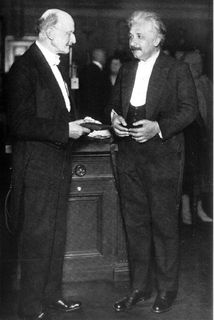 Photo en noir et blanc de deux hommes debout, en habit de soirée et discutant ensemble