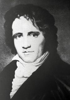 Black and white portrait of a man with curly hair wearing a black jacket and white collar