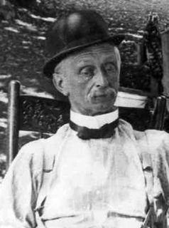 Photo en noir et blanc d'un homme portant un chapeau melon, une moustache, un noeud papillon et une chemise blanche.