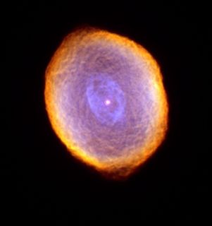 Photo of a luminous dot at the centre of a cloudy blue, purple, pink and orange mass against a very black background