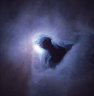 Photo of a luminous white spot surrounded by a grey and purple cloudy mass with a darker centre